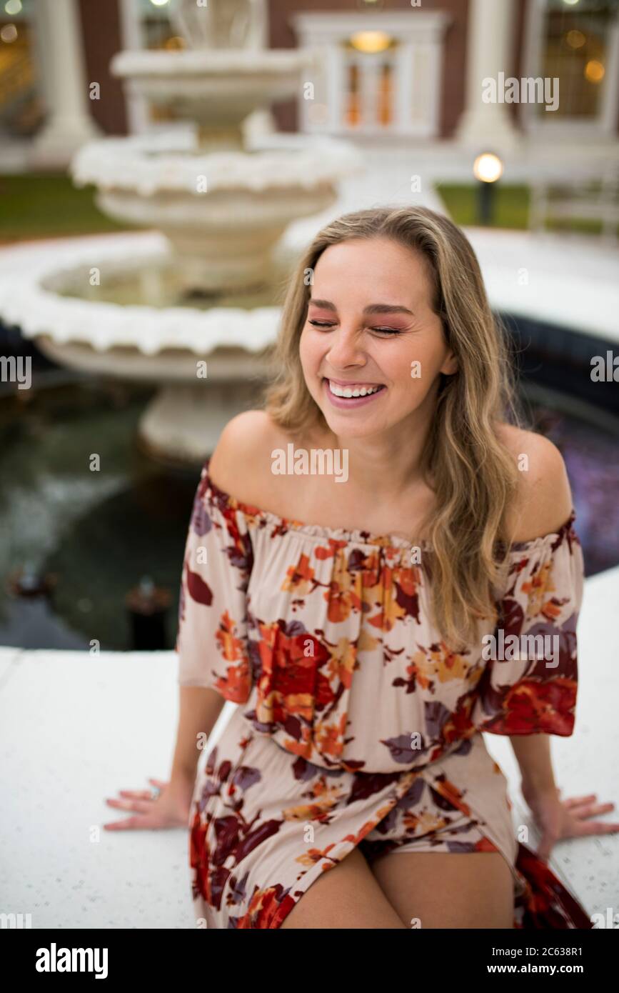college student laughing by a fountain in a courtyard Stock Photo