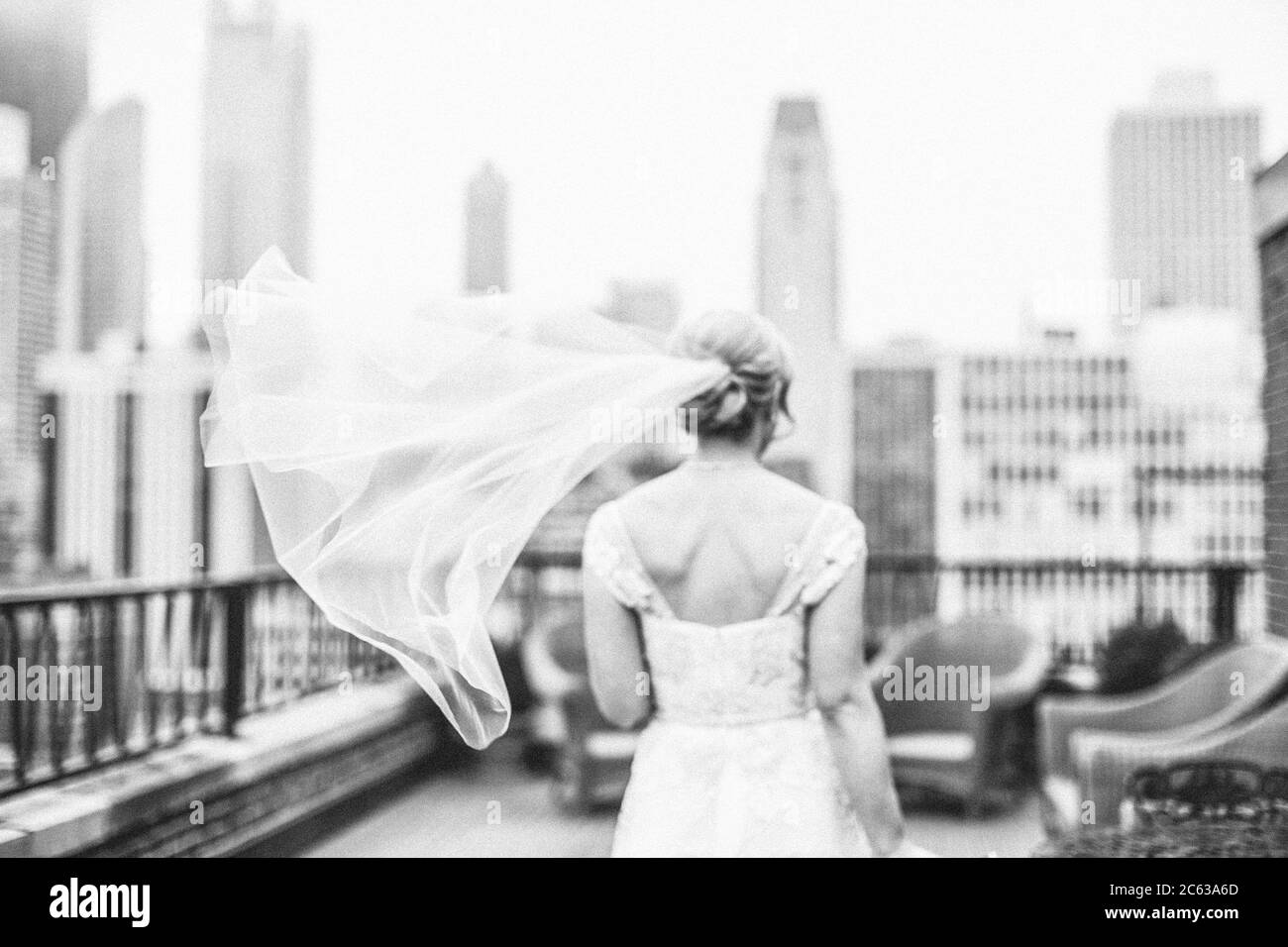 Bride on balcony walking away with veil flying Stock Photo