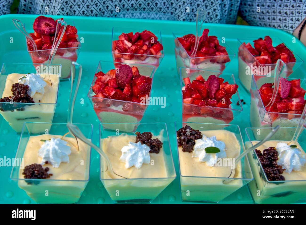 A young girl brings a pudding treat with a fruit decoration on top. Desserts  are served for tasting and quality assessment Stock Photo - Alamy