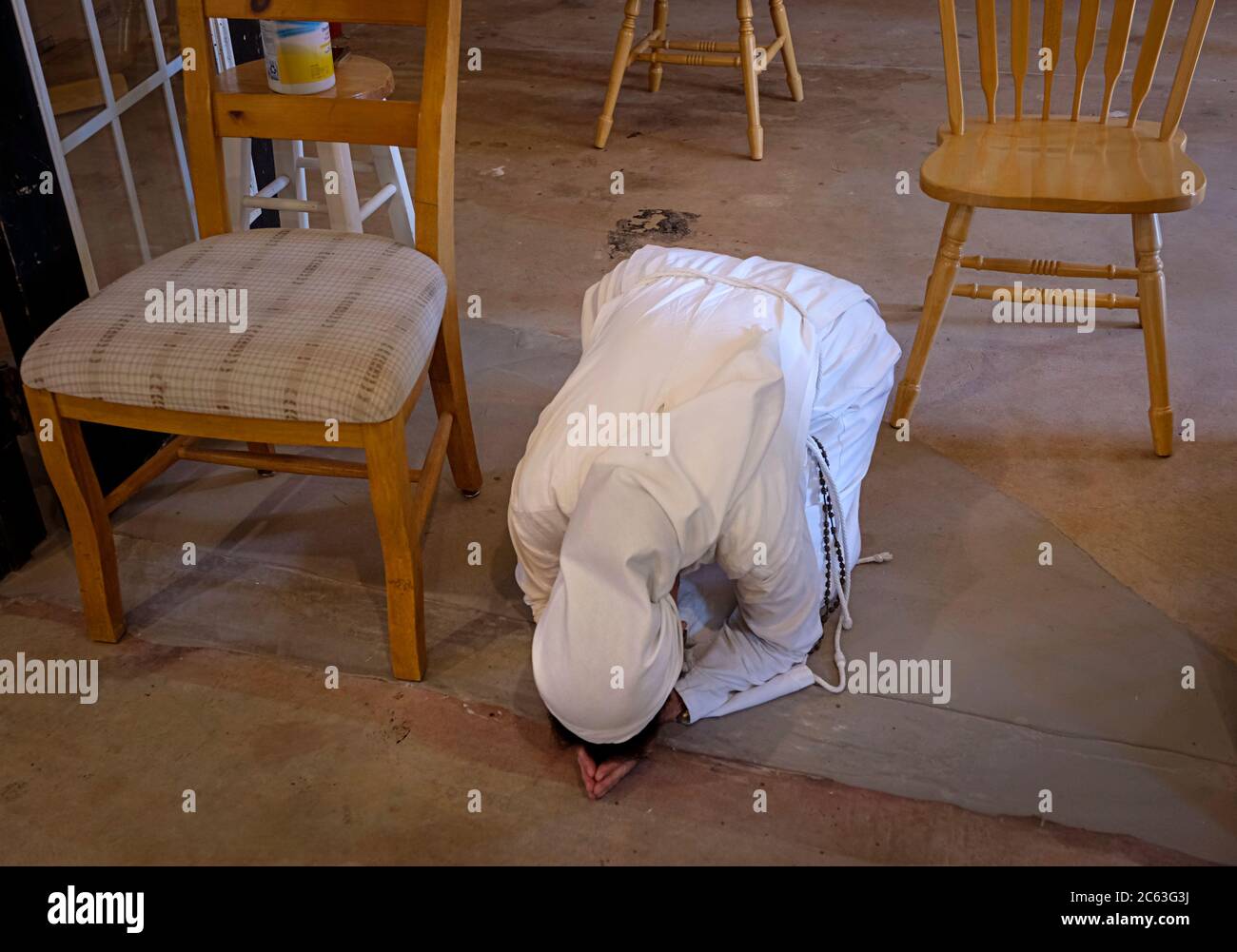 Catholic nun praying on the ground of a barn used as a chapel Stock Photo