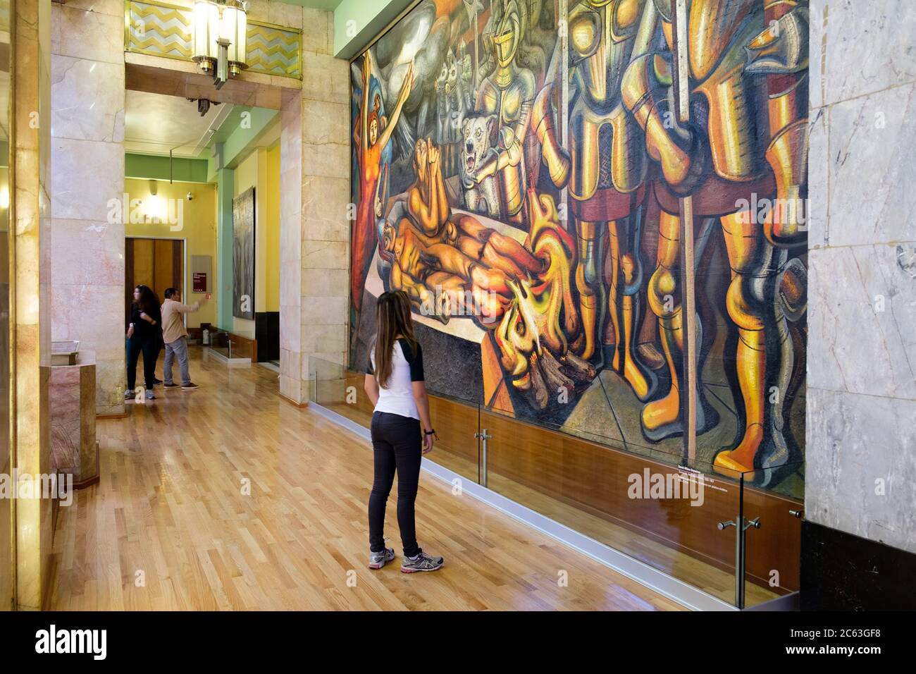 Visitor admiring a famous mural painting by David Alfaro Siqueiros at the museum of Palacio de Bellas Artes in Mexico City Stock Photo