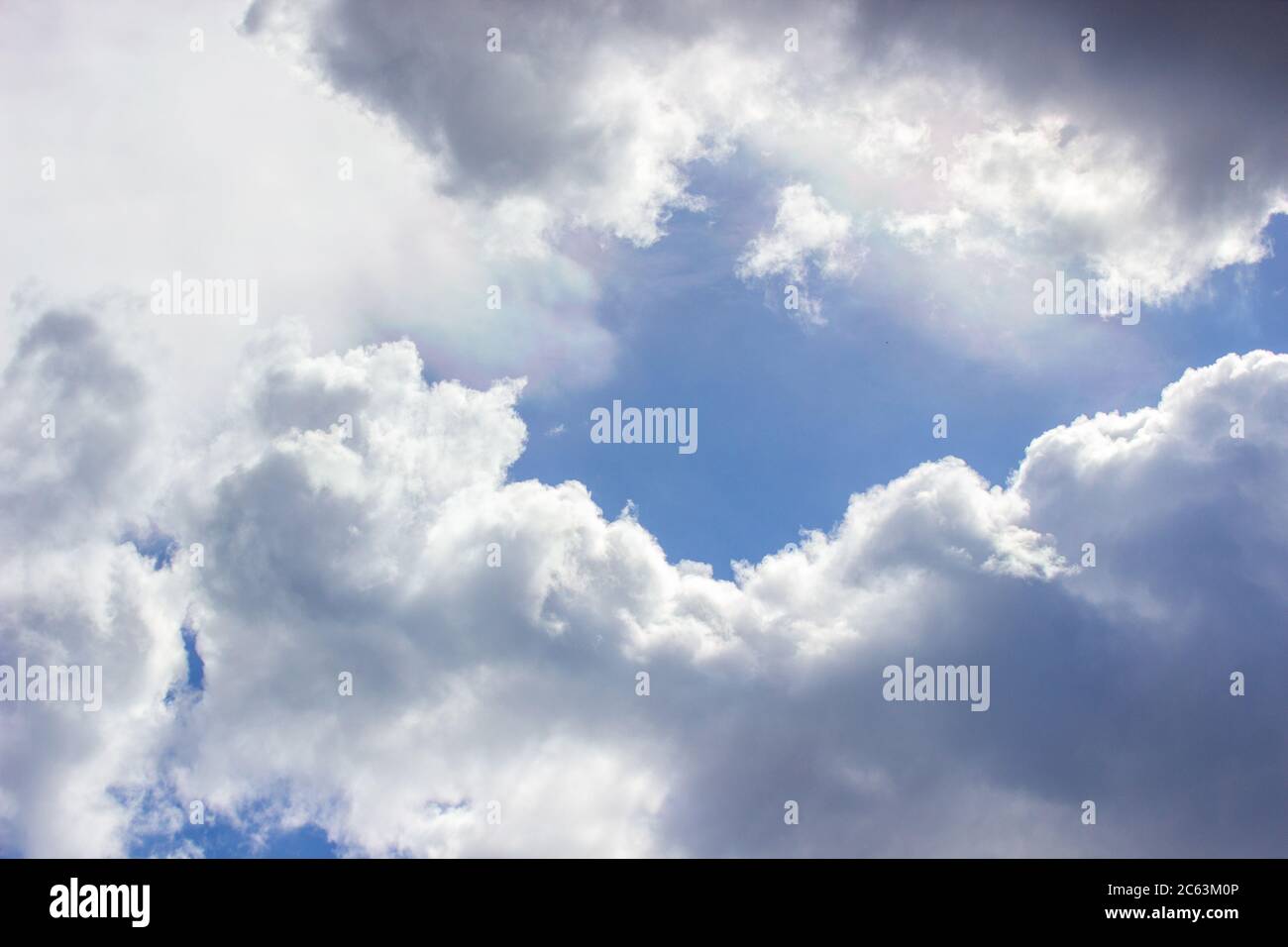 White clouds in the blue sky. The rays of the sun make their way ...