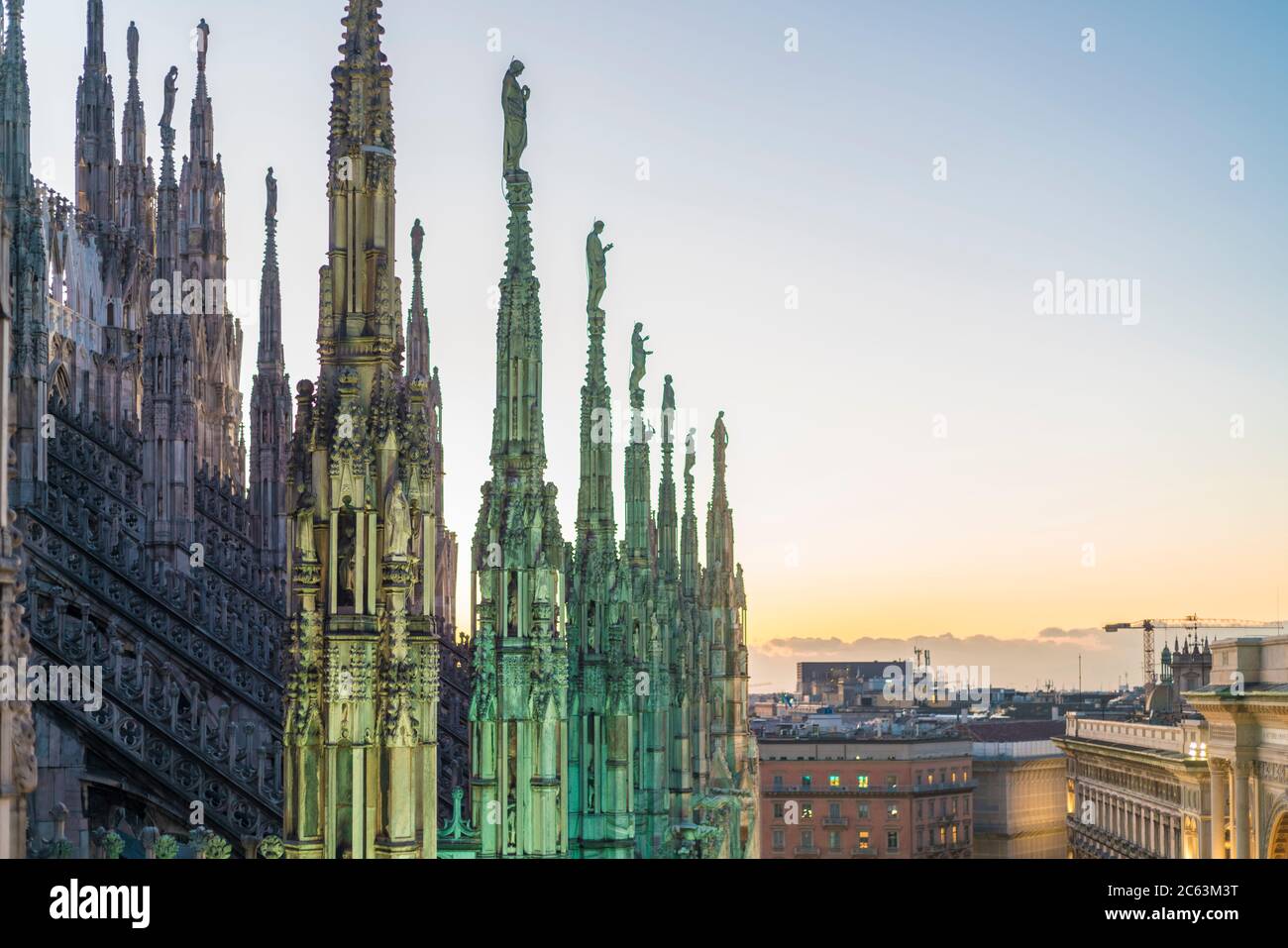 The stretched statue pillars on the top of the Cathedral in Milan before the sunset Stock Photo