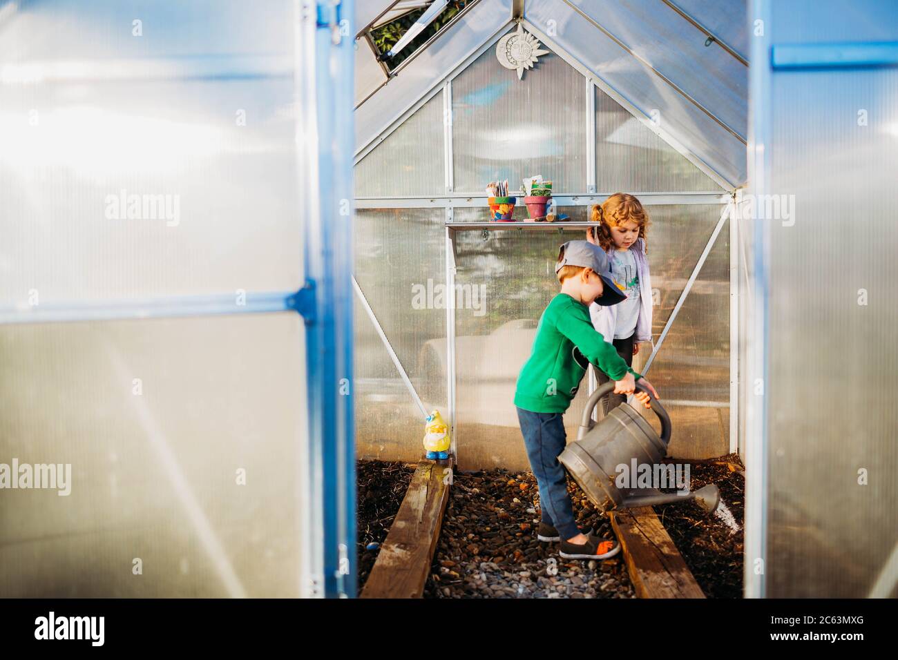 Two young kids taking care of plants in greenhouse Stock Photo