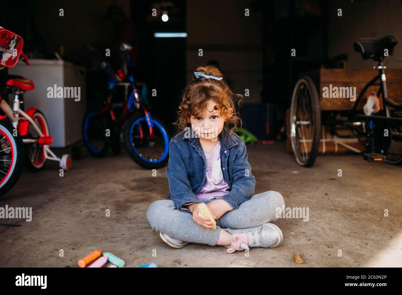Young girl sitting in garage coloring with chalk in spring Stock Photo ...