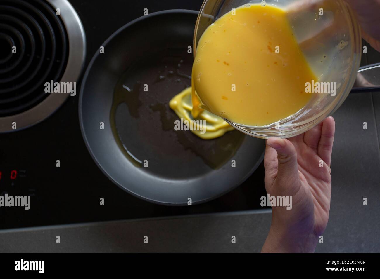 Pouring egg mixture into frying pan Stock Photo Alamy