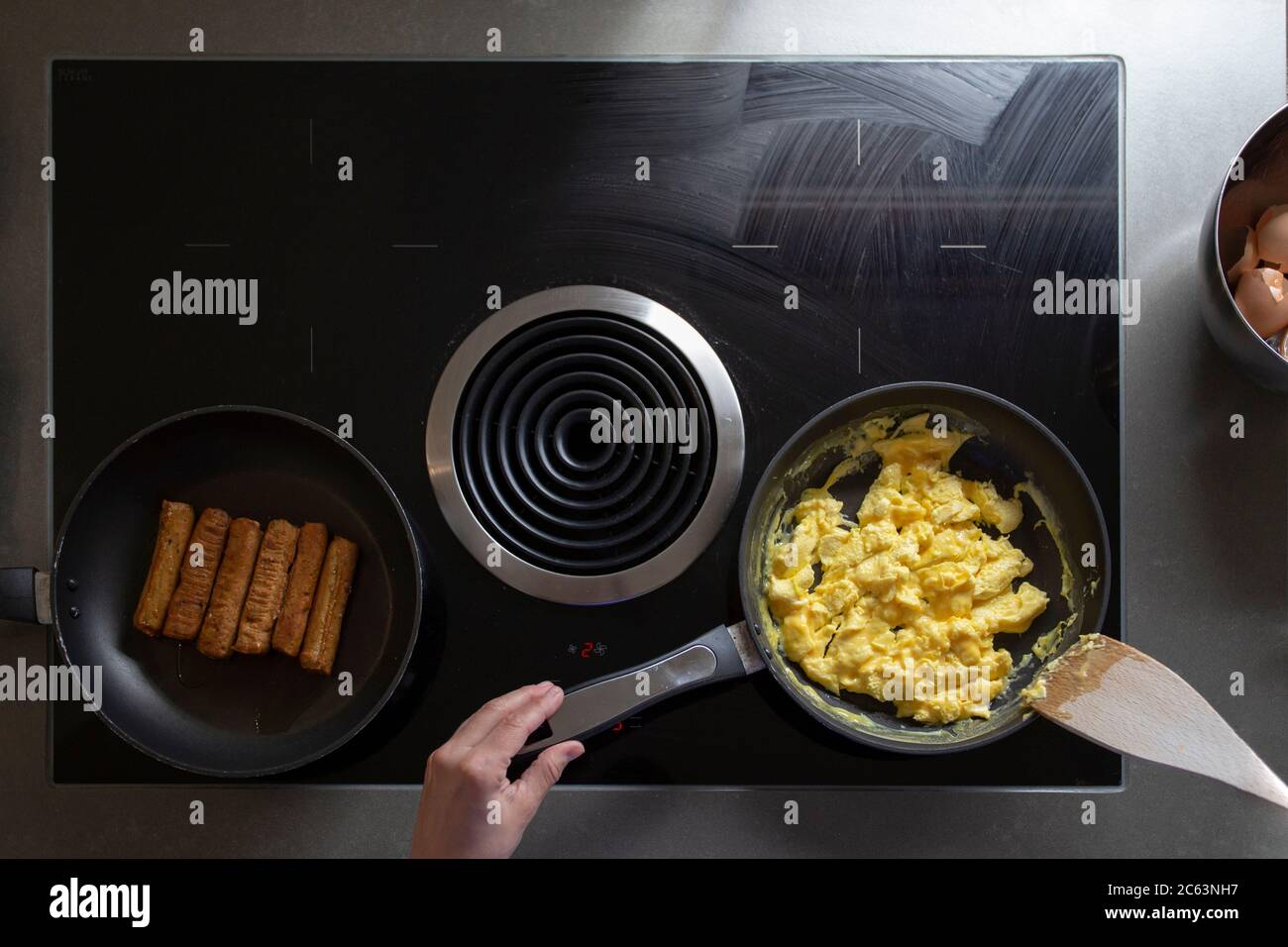 Overhead view of someone cooking scrambled eggs and sausage Stock Photo