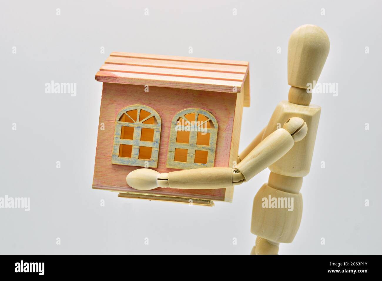 Wooden mannequin carrying a house in his arms Stock Photo