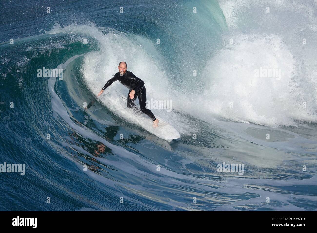 Older male surfer riding a large, beautifully curling wave Stock Photo