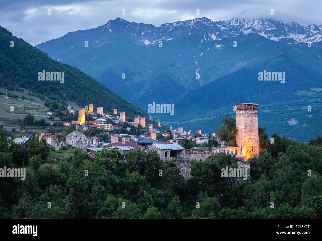 Dusk view of the Svanetian towers in Mestia with the mighty Caucasus Mountains in the background, Svanetia, Georgia. Stock Photo