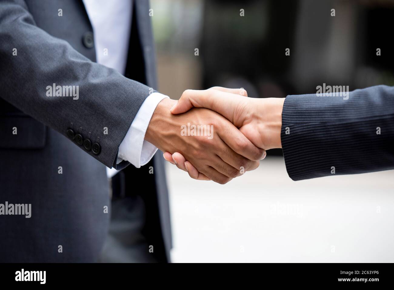 Businessman in formal suit making handshake with partner outdoors Stock Photo