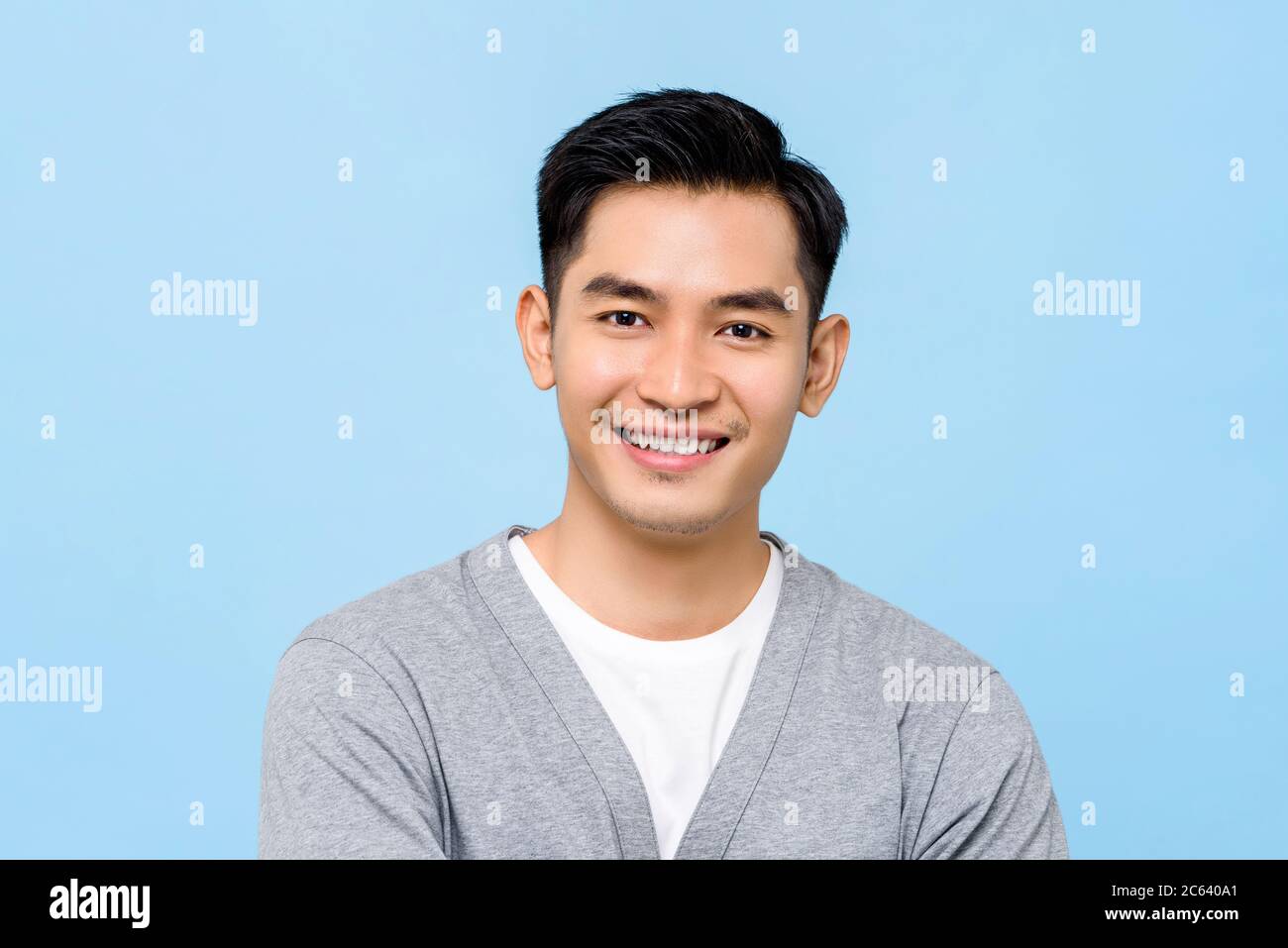 Handsome portrait of young Asian man smiling isolated on light blue background Stock Photo