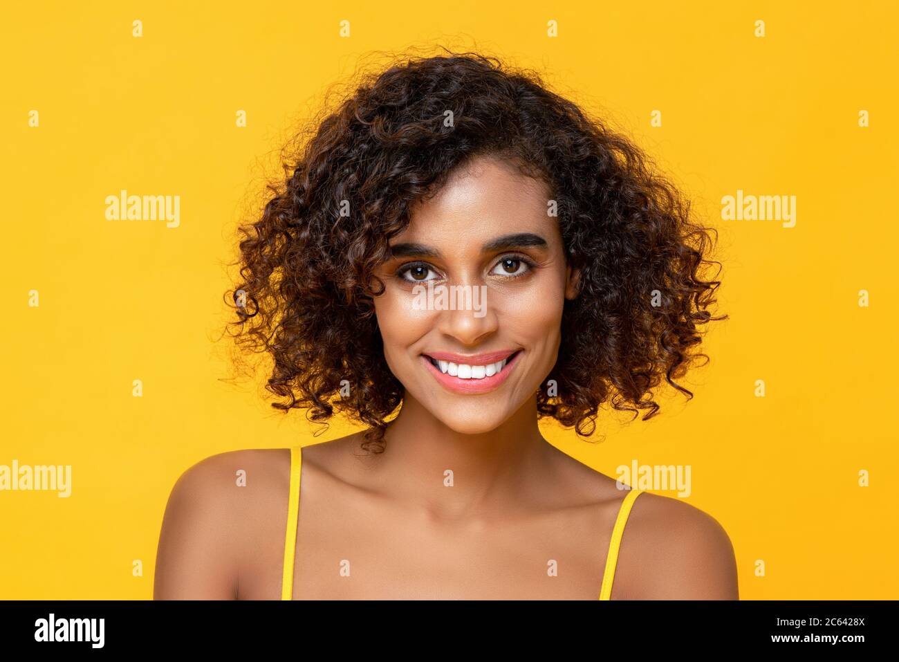 Happy smiling curly hair beautiful woman looking at camera isolated on  yellow background Stock Photo - Alamy
