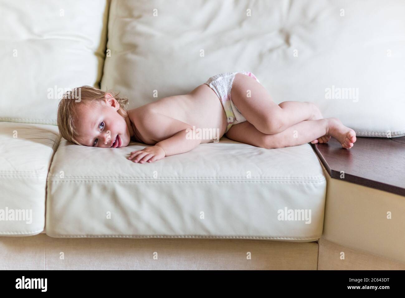 Cute baby girl in diapers lying on bed Stock Photo Alamy