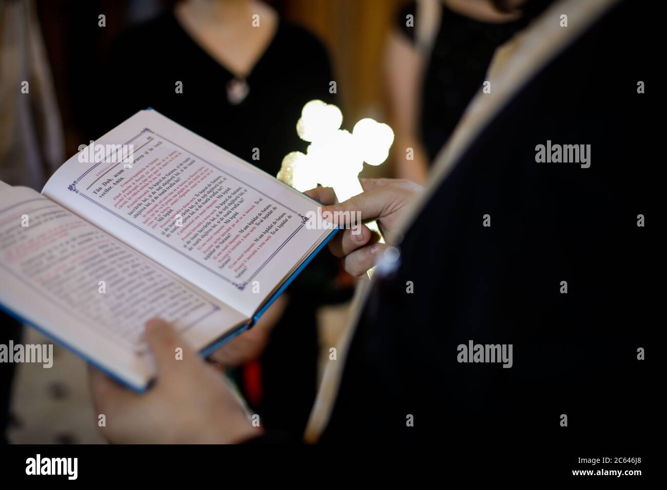 Bucharest, Romania - May 24, 2020: Details with the hand of an Orthodox priest holding a Bible and a cross during an Orthodox Baptism. Stock Photo