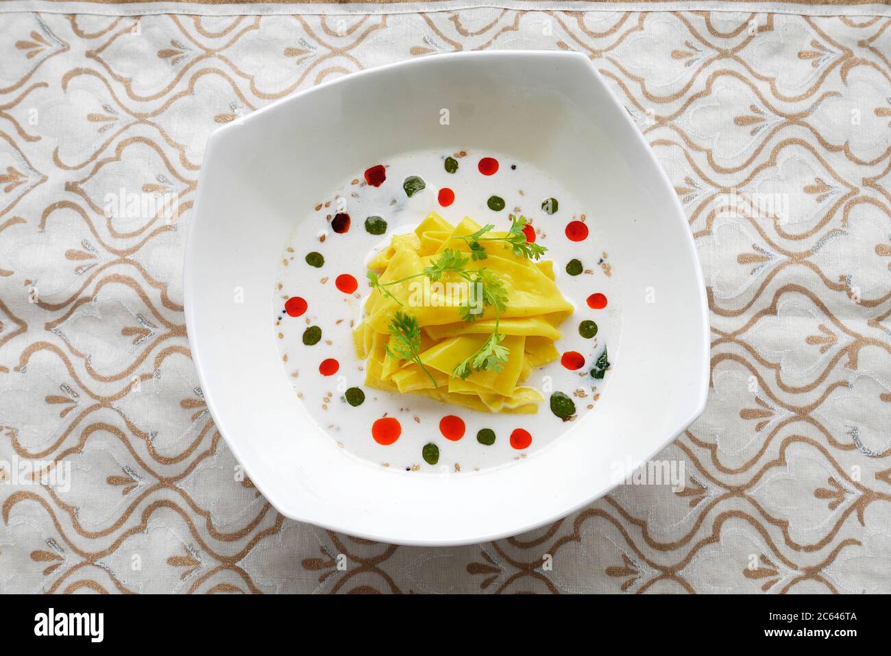 KHANDVI IN A BOWL WITH COCONUT MILK WITH BASIL OIL AND CHILY OIL Stock