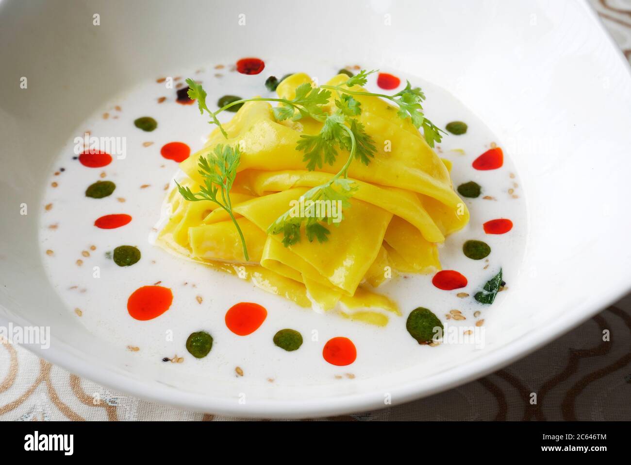 KHANDVI IN A BOWL WITH COCONUT MILK WITH BASIL OIL AND CHILY OIL Stock