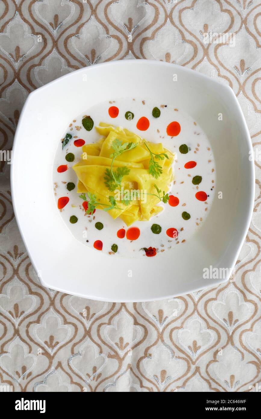 KHANDVI IN A BOWL WITH COCONUT MILK WITH BASIL OIL AND CHILY OIL Stock
