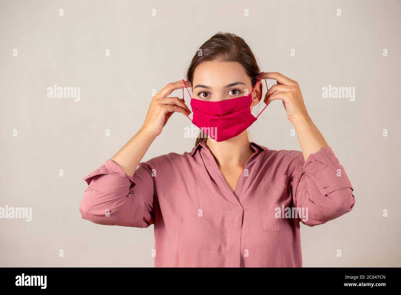 Young girl putting on a protective face mask during a Covid-19 pandemic. Stock Photo
