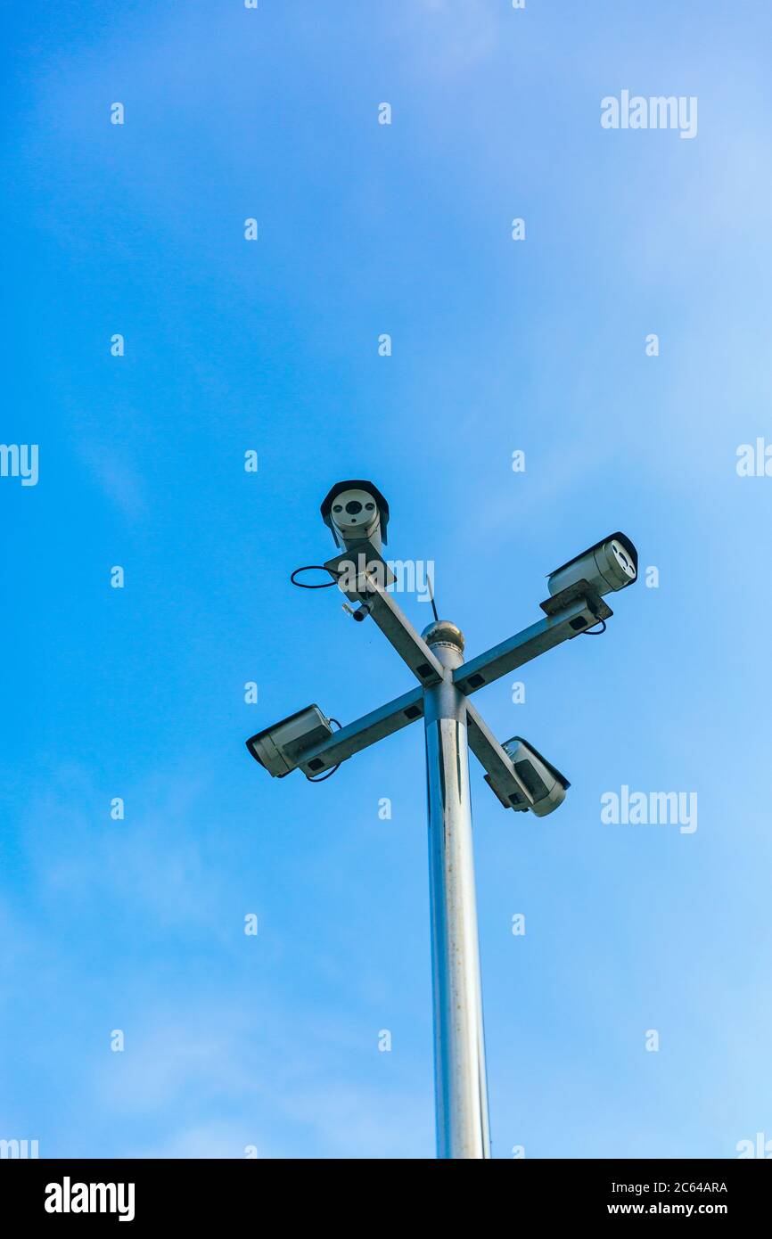 Surveillance camera mounted on a pillar under a blue sky Stock Photo