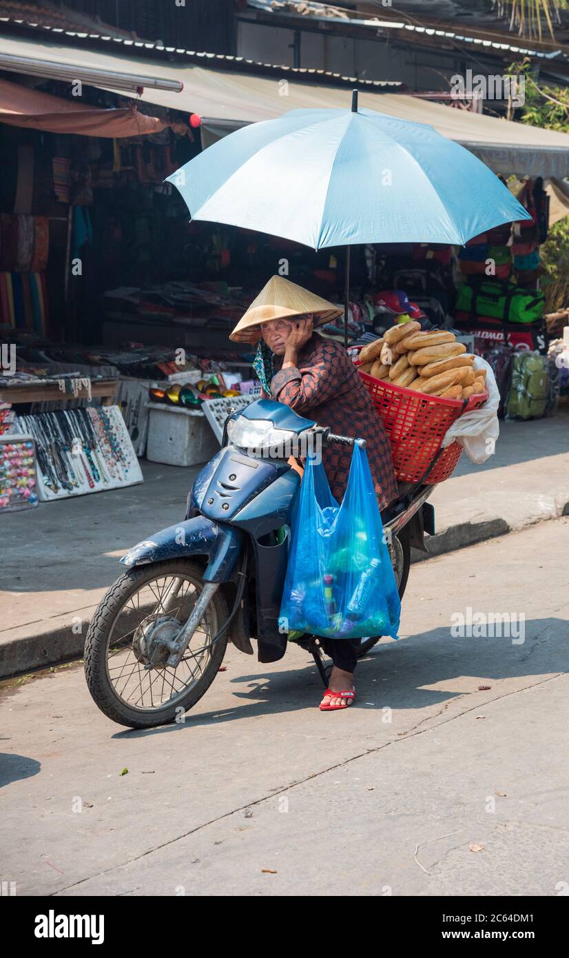 An old local Vietnamese lady feeling the heat on a hot day in Hoi-An Vietnam Asia. Stock Photo