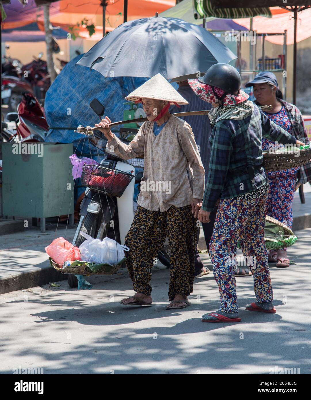 Local elderly Vietnamese lady carrying traditional Vietnamese yoke in the market town of Hoi An Vietnam  Asia. Stock Photo