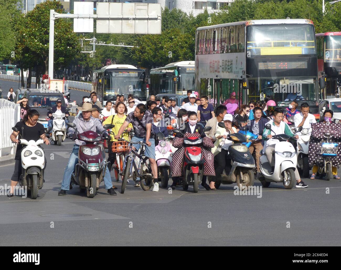 Local Chinese people riding motorcycles waiting at a busy road crossing in the City of Kunming South West China Stock Photo