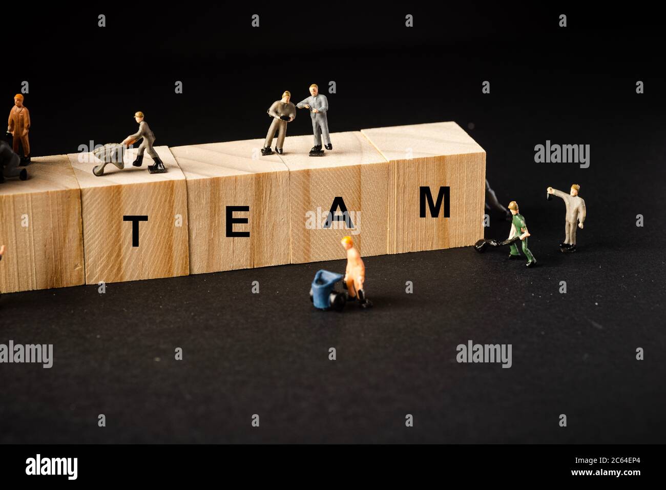Teamwork concept. Miniature builders figure with wooden blocks with ...