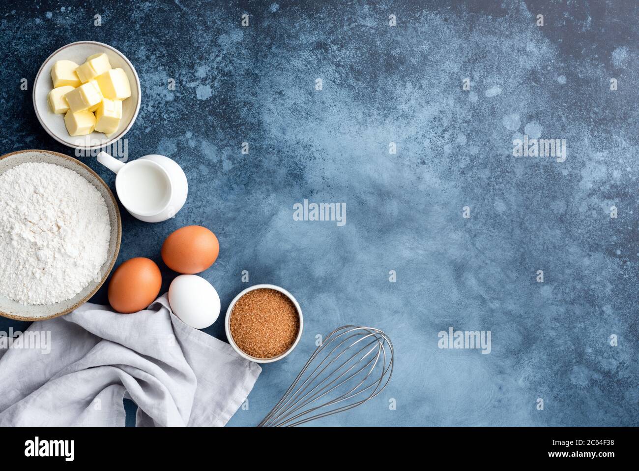 Baking ingredients flour eggs sugar milk and butter on a painted blue