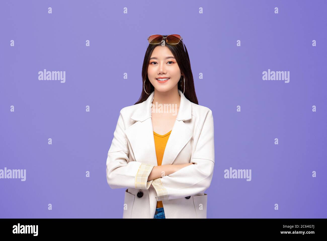 Portrait of young pretty smiling Asian woman in smart casual clothes crossing arms on colorful purple background Stock Photo