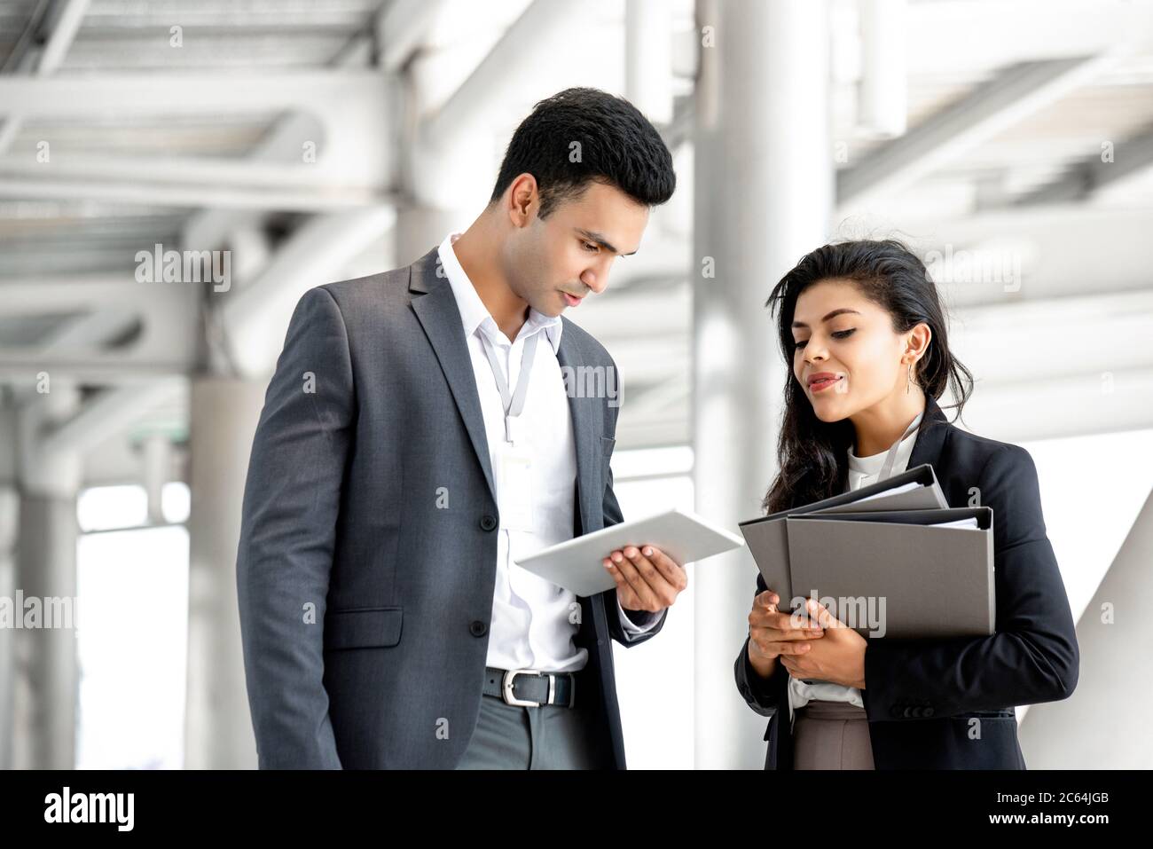 Portrait of two young business colleagues discussing while looking at tablet outside the office Stock Photo