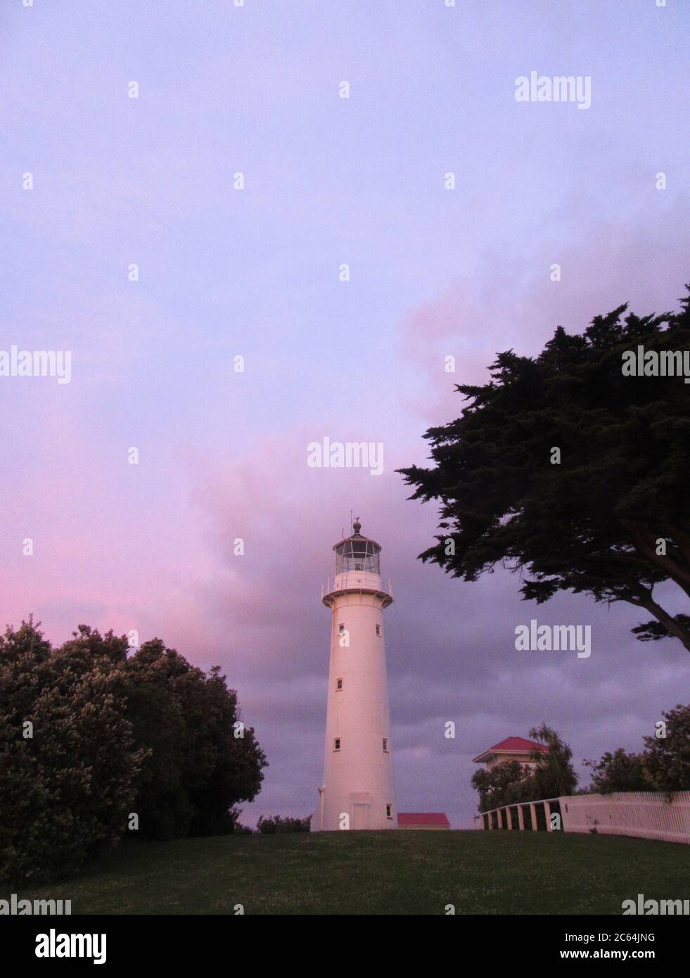 Lighthouse on Tiritiri Matangi Island in the Hauraki Gulf, New Zealand. During purple colored sunset. Stock Photo