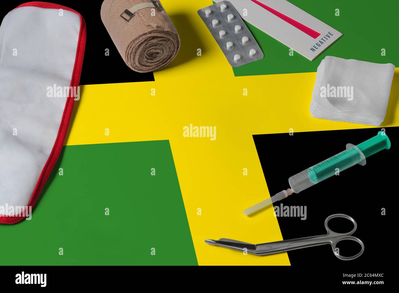 Jamaica flag with first aid medical kit on wooden table background. National healthcare system