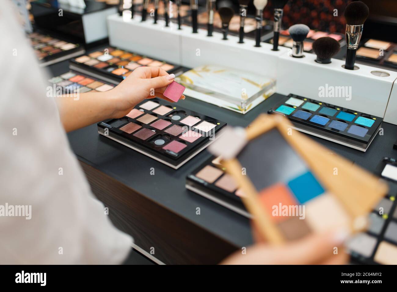Woman holds eyeshadows at shelf in cosmetics store Stock Photo Alamy