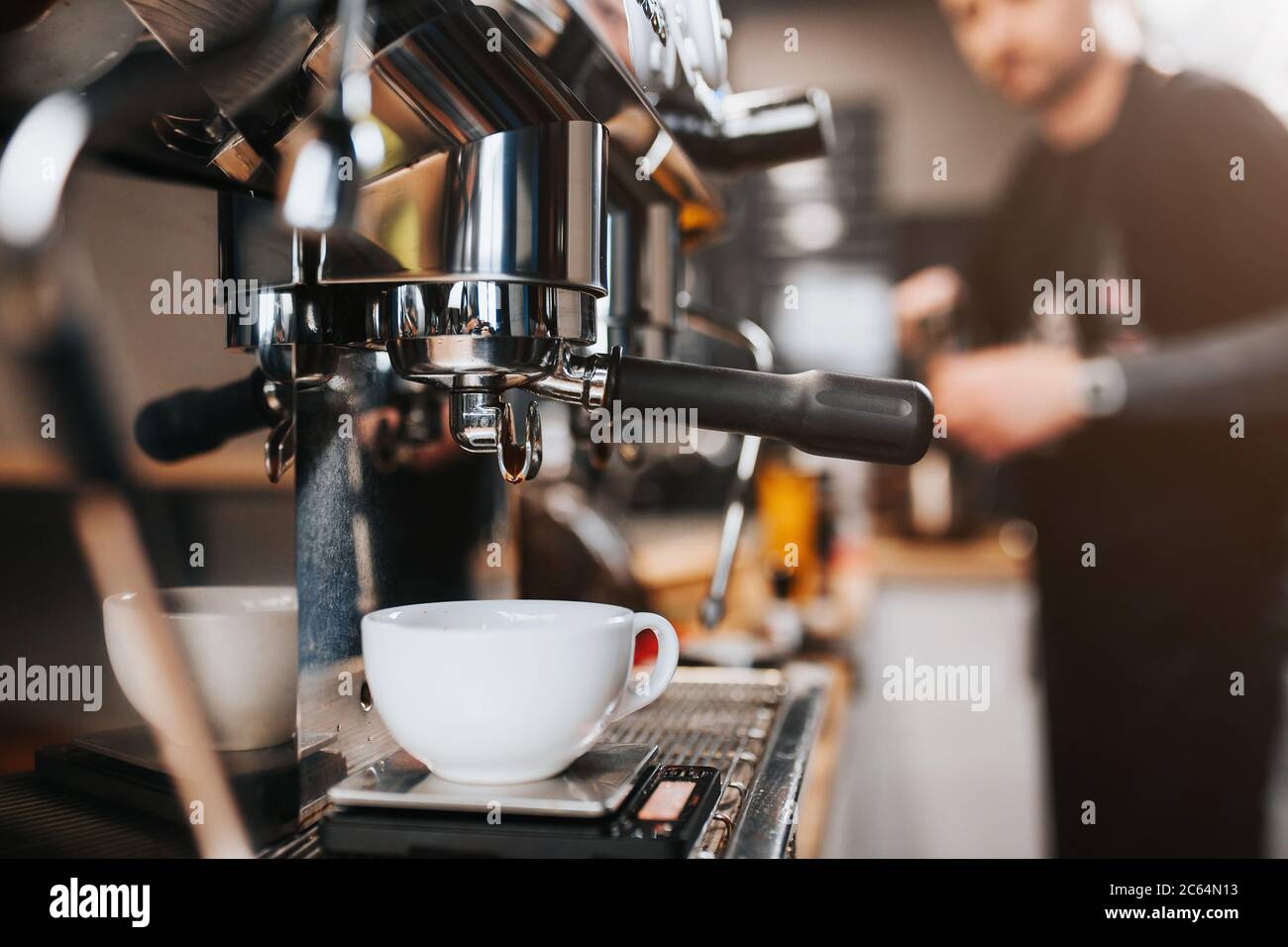 https://c8.alamy.com/comp/2C64N13/close-up-coffee-machine-with-a-white-cup-for-coffee-barista-in-the-background-in-defocus-cafe-and-bar-concept-2C64N13.jpg