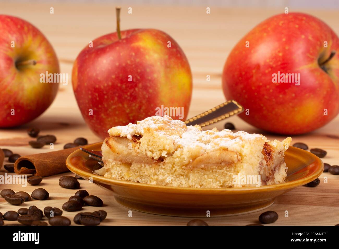 Apple pie on a plate with apples, coffee and cinnamon in the background Stock Photo