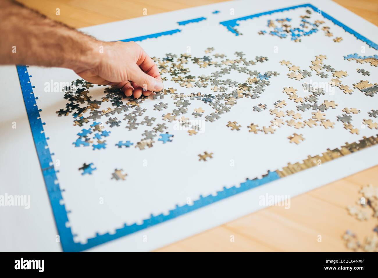 A complex puzzle on a white table - many similar solid pieces - a  painstaking task Stock Photo - Alamy