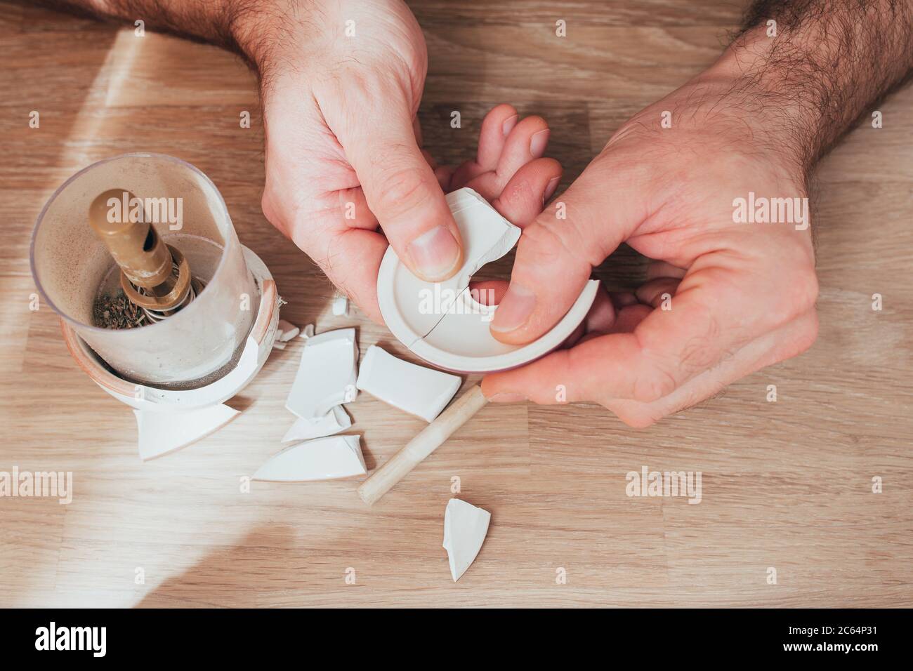 Repairing a beloved vase broken on the floor pieces of ceramics in the hands of a man trying