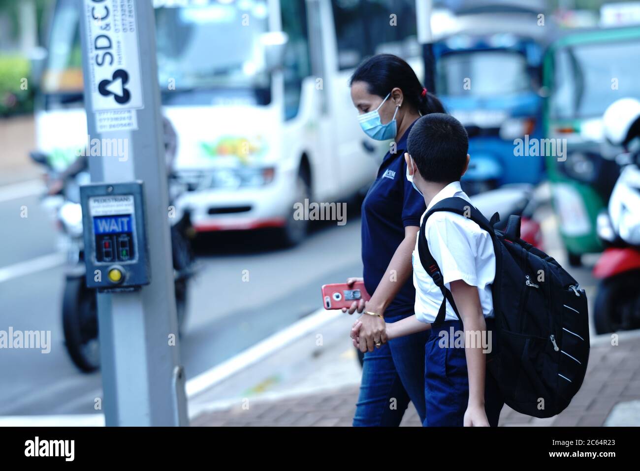 Colombo, Sri Lanka. 7th July, 2020. A woman escorts her son crossing a road  to go to school in Colombo, Sri Lanka, July 7, 2020. According to Sri  Lankan Ministry of Education,