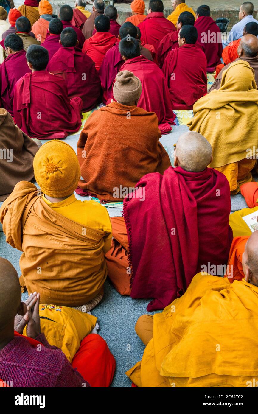 Small group of buddhist praying monks seen from behind in Lumbini, Nepal. Wear colorful thick robes and beanies in winter time for keeping warm Stock Photo