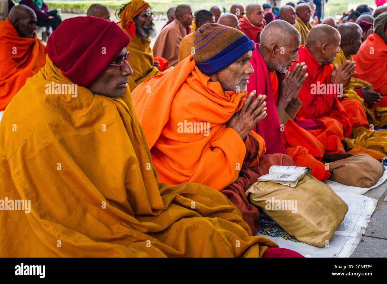 Lumbini, Nepal - December 21st 2012. Austere experienced old nepali buddhist monk prays sits in a row amongst others. wear thick robes and beanie hat Stock Photo