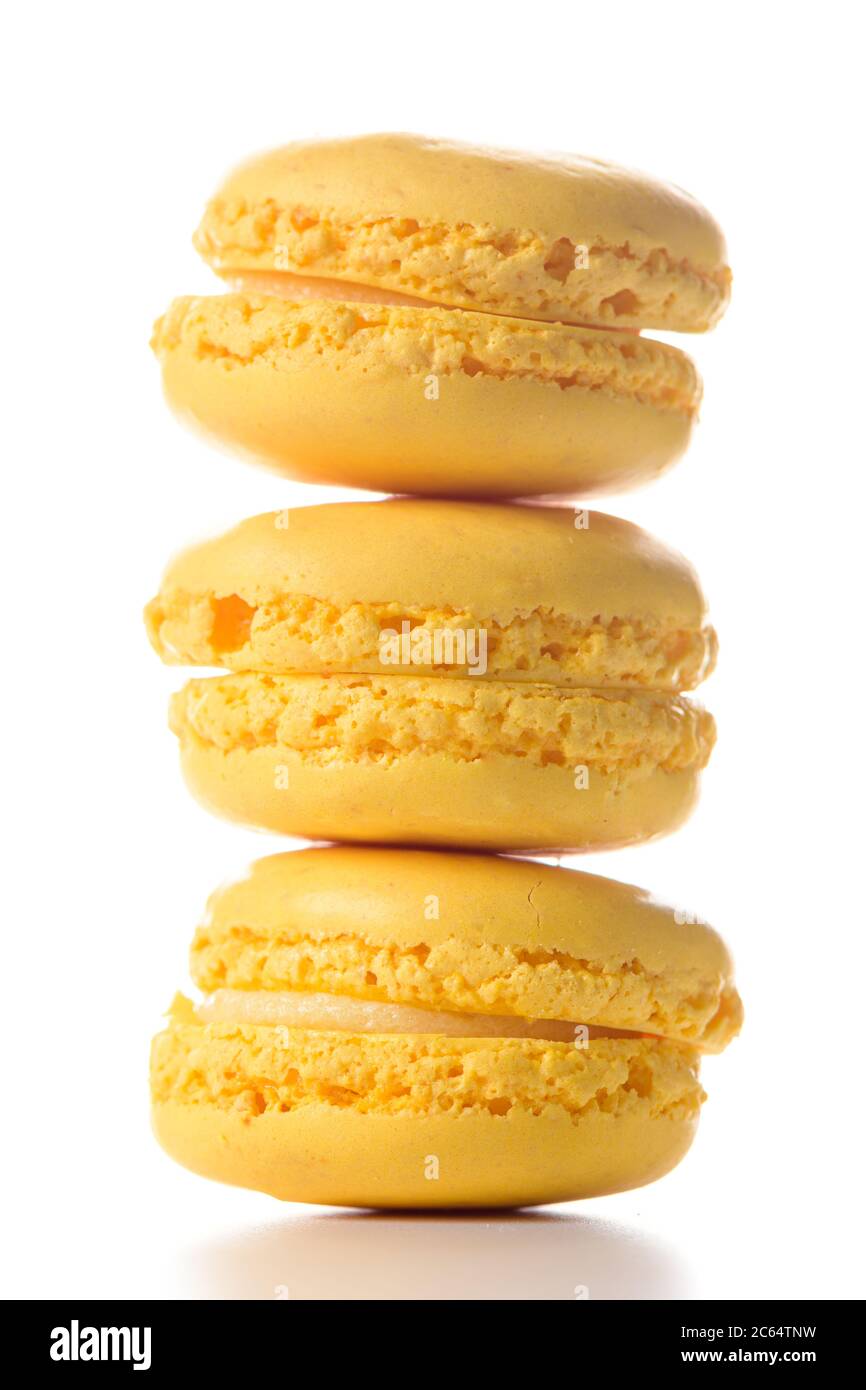 Three lemon flavoured macaroons standing on top of each other on white ...