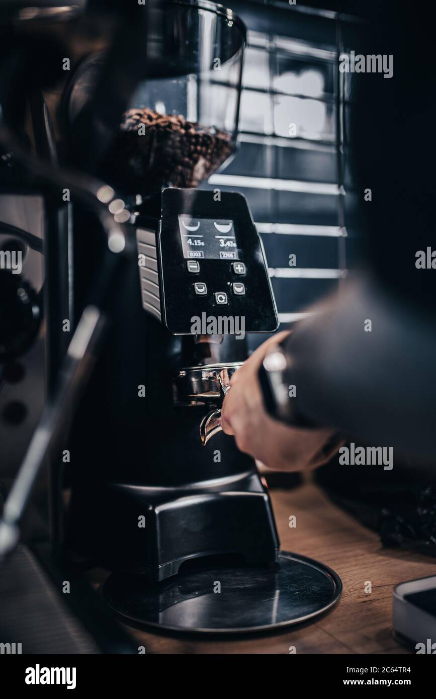 Barista picks up ground coffee from a coffee grinder to a holder
