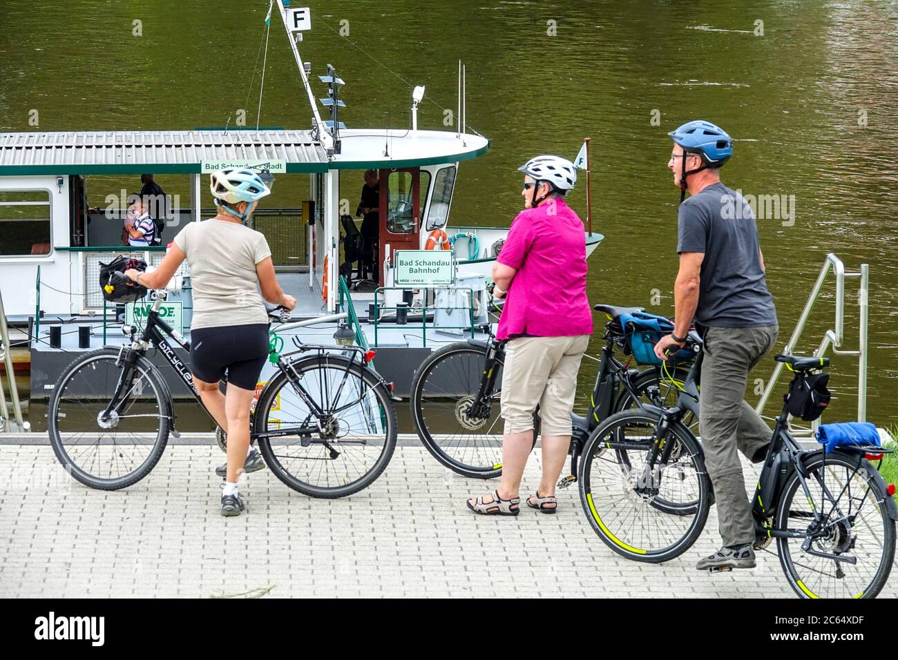 Elbe river ferry boat and seniors on bicycles Bad Schandau Germany people on the cycle path, people waiting to embark, boarding Stock Photo