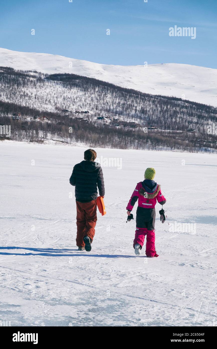 Rear view of two boys walking on frozen lake in Vasterbottens Lan, Sweden. Stock Photo