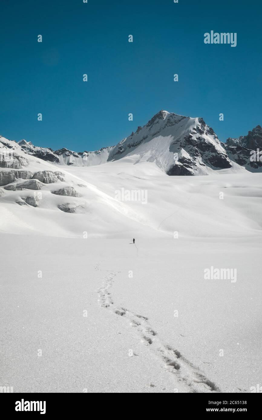 Hiking on the Snowfields of Indian Himalayas with the high altitude panoramic view of higher mountains in mountaineering Stock Photo