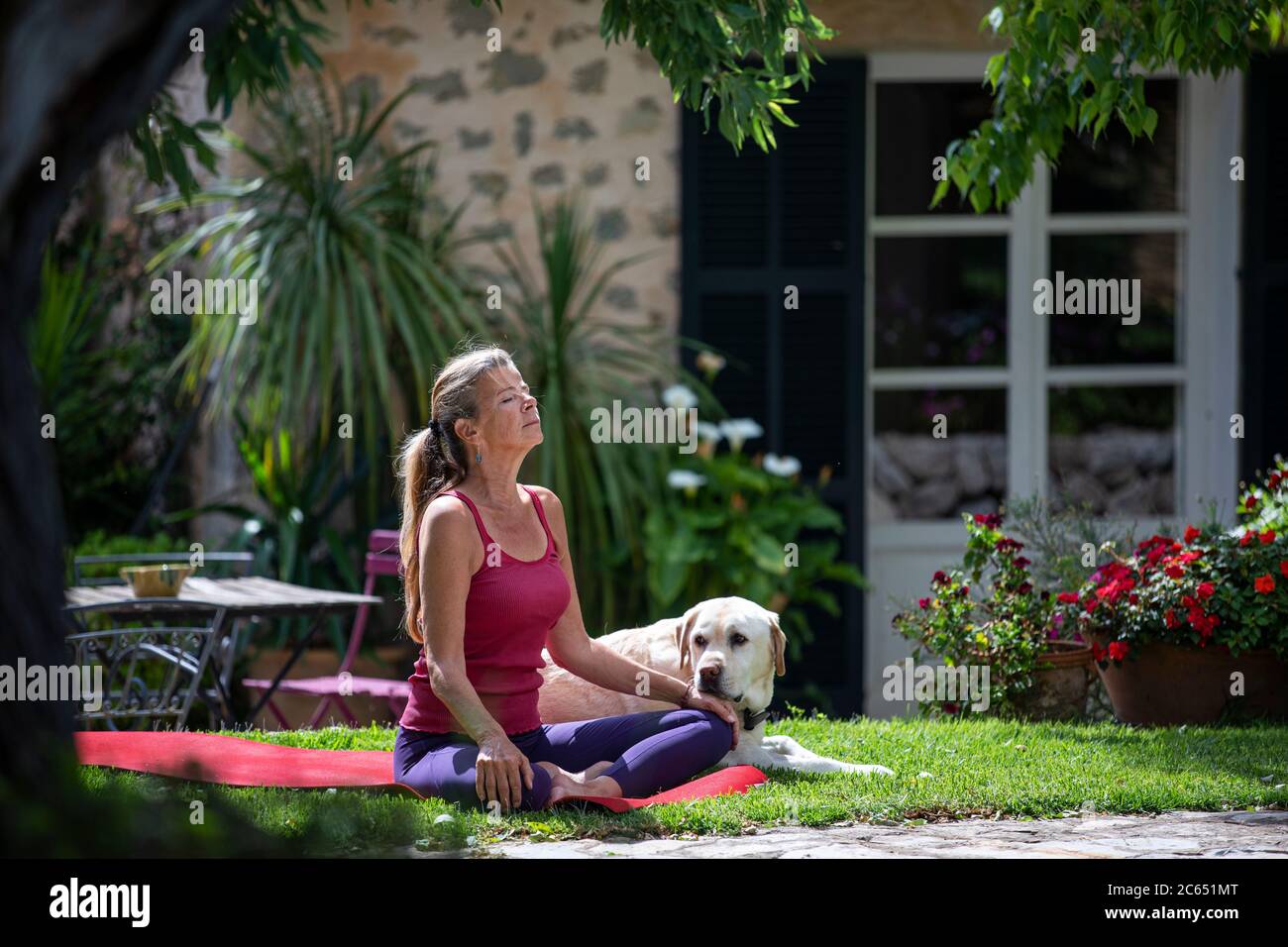 Woman practicing yoga outdoors on lawn in garden. Stock Photo