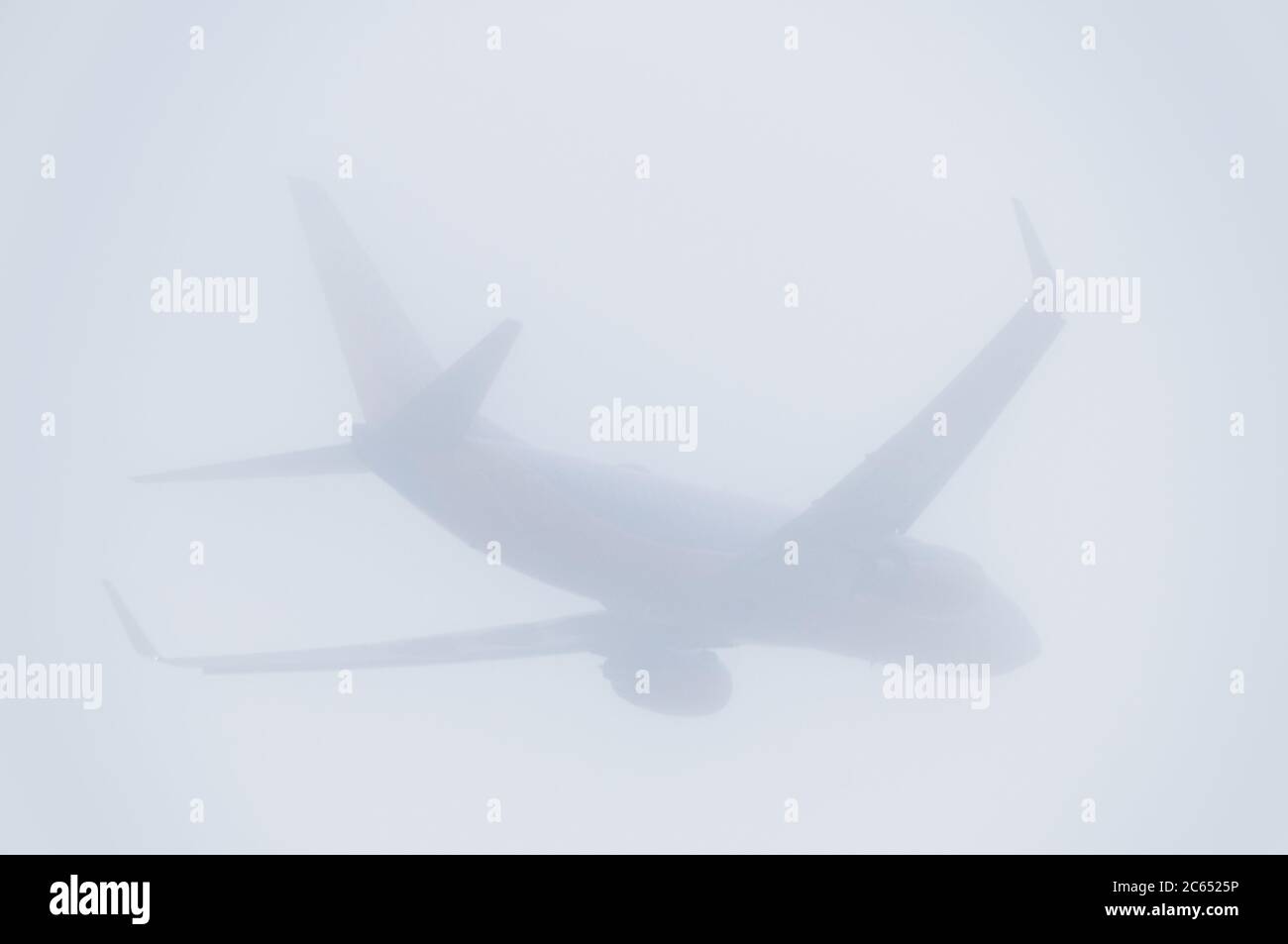 Boeing 737 Jet Airplane Flying in Fog Stock Photo