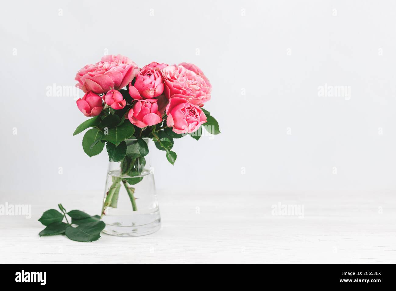 Romantic bouquet of pink roses in a glass vase on a white background ...