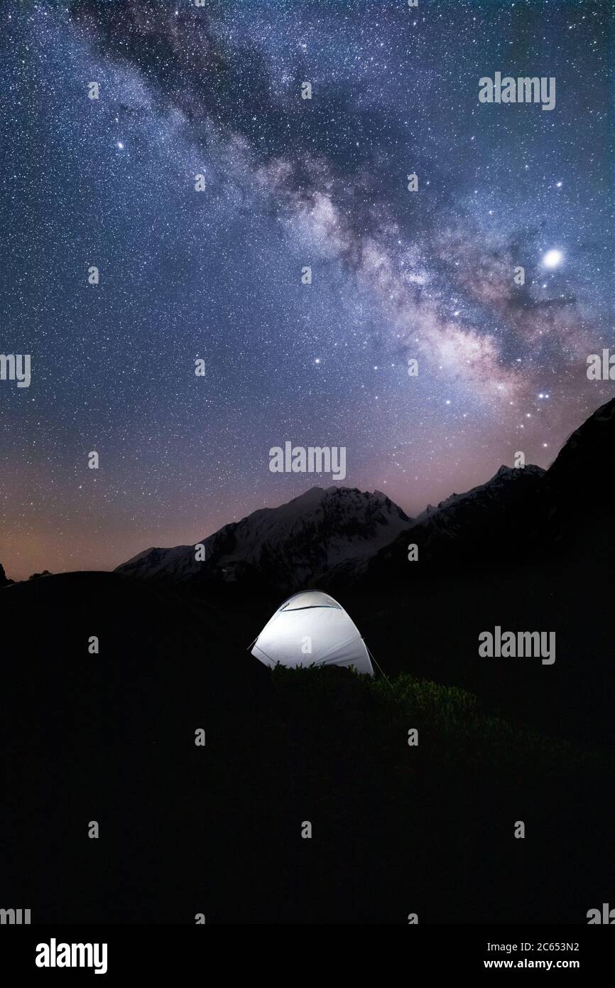 The shiny bright milky way galaxy with a tent in the foreground captured late in the night on an expedition in the Indian himalayas Stock Photo